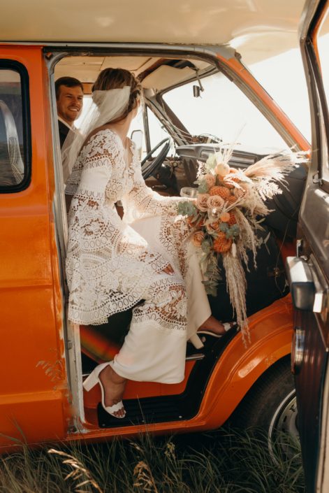 Orange boho bride coming out of orange van with orange boho bouquet