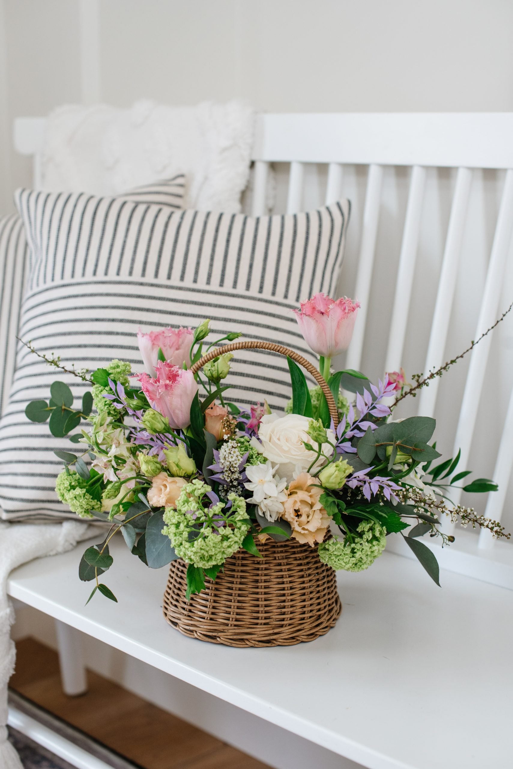 A medley of spring coloured flowers with a garden vibe designed into a beautiful woven basket