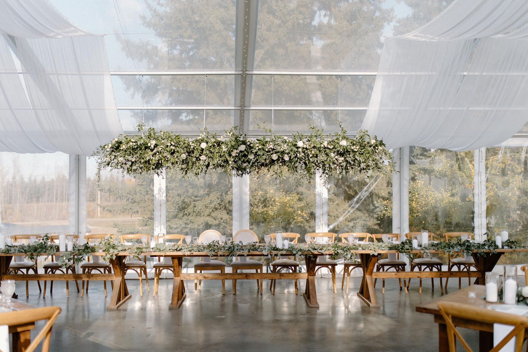 Large floral chandeliers hanging over the head table decorated with eucalyptus leaves