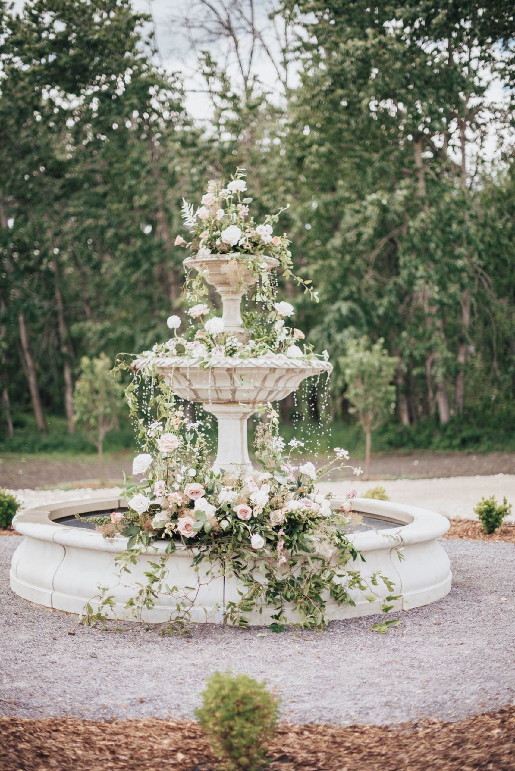 Large outdoor fountain draped in wedding florals and greenery