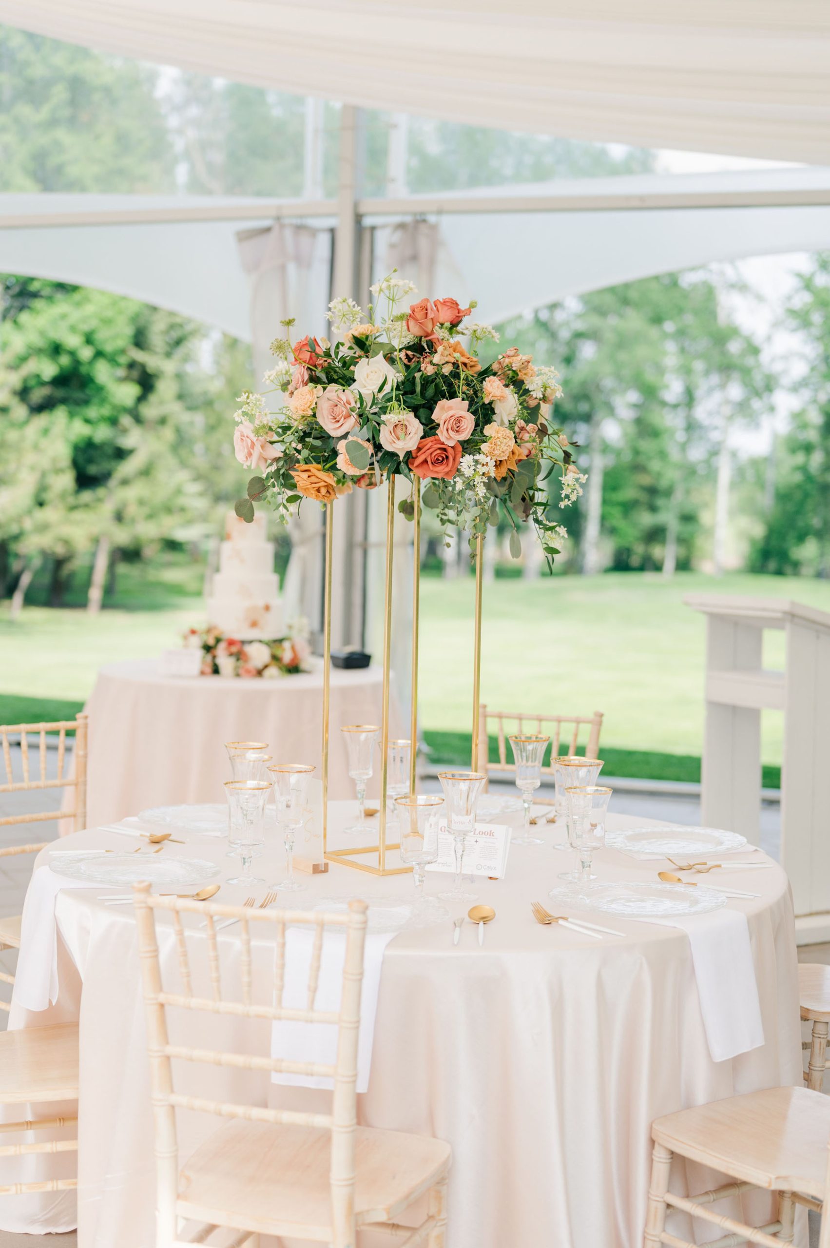 High wedding centerpiece on gold stand with rust, blush and pink shades of florals