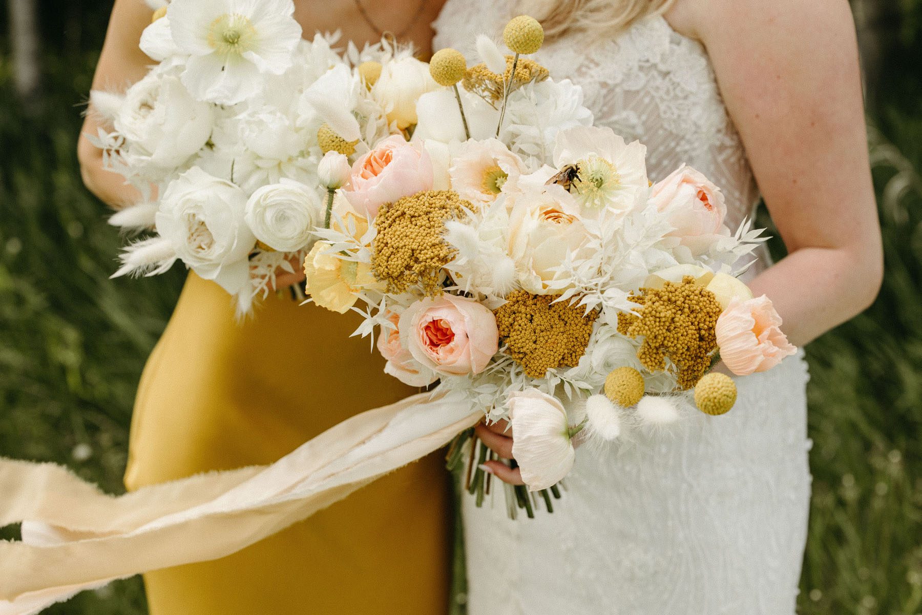 Mustard yellow bouquet with blush and white florals and feathers