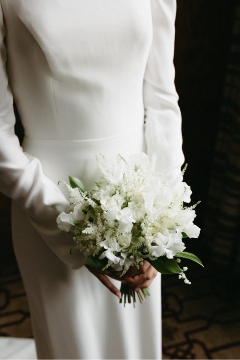 A close up of our bride holding a delicate posy bouquet in all white