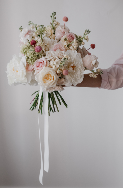holding a bouquet with white, pink and blush flowers typically found in Calyx floral subscription hand tied arrangments