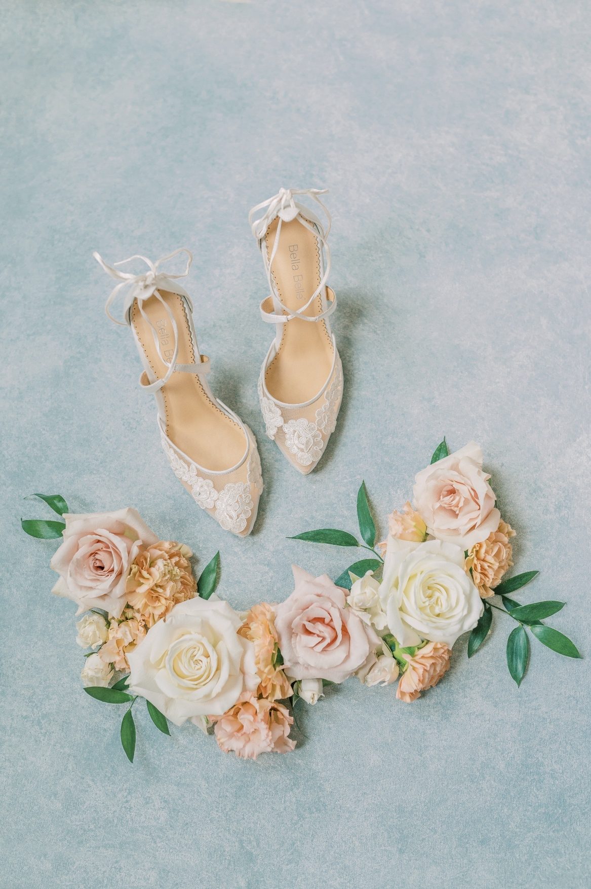 A semi circle cluster of pretty white, peach and blush blooms and the bridal shoes