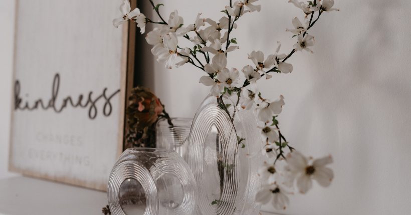 An assortment of vases on a mantle with white flowering branches sticking out of one of them