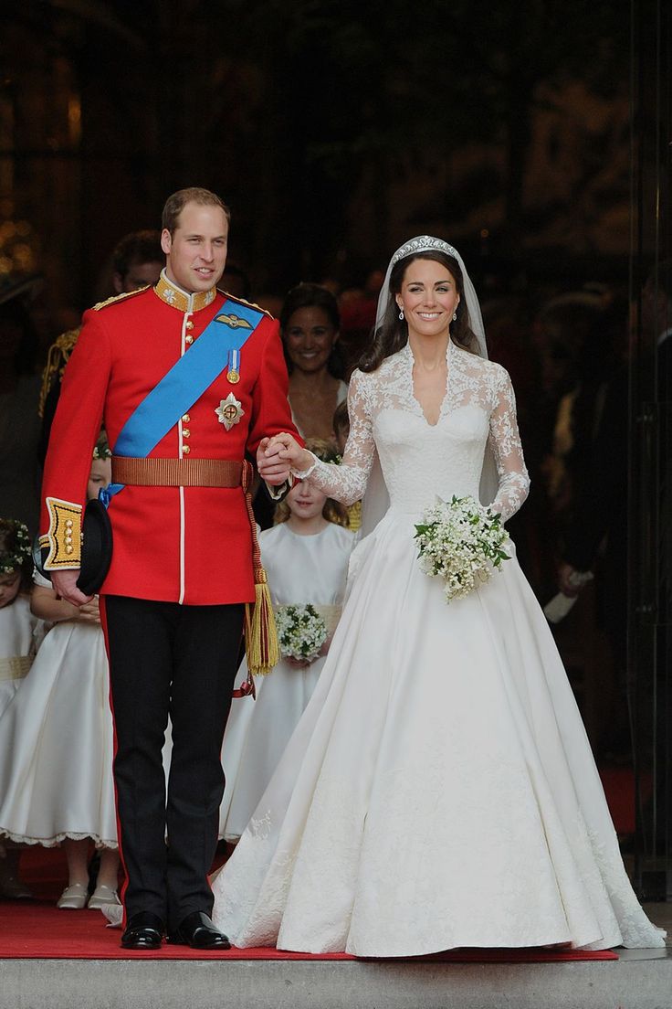 Prince William and Princess Kate on their royal wedding, holding hands and Kate clasping an all white posy bouquet