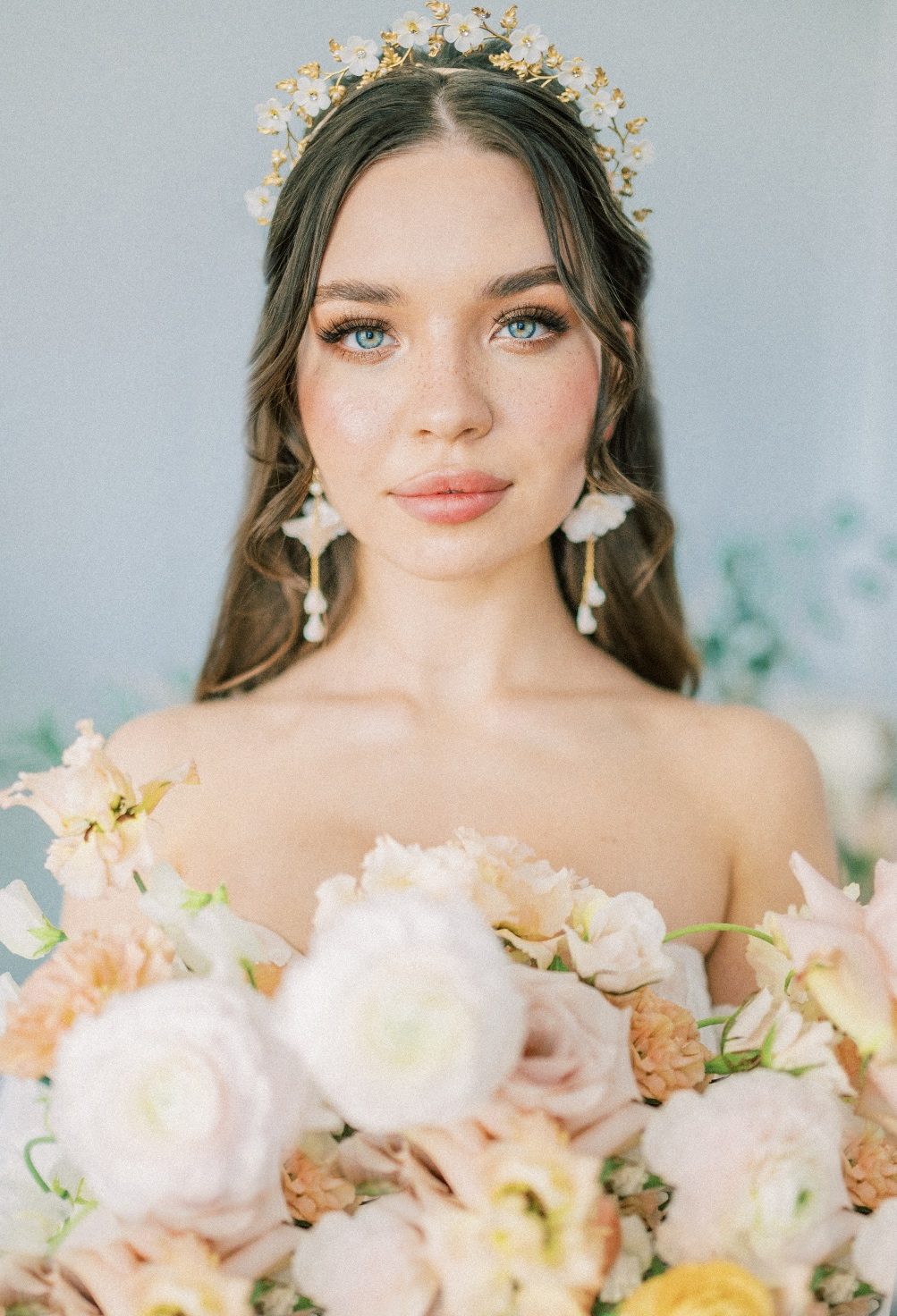 A close up of our radiant model, Uliana (@ulyashh_) with her gorgeous make up and earrings, showing just the top of her bridal bouquet