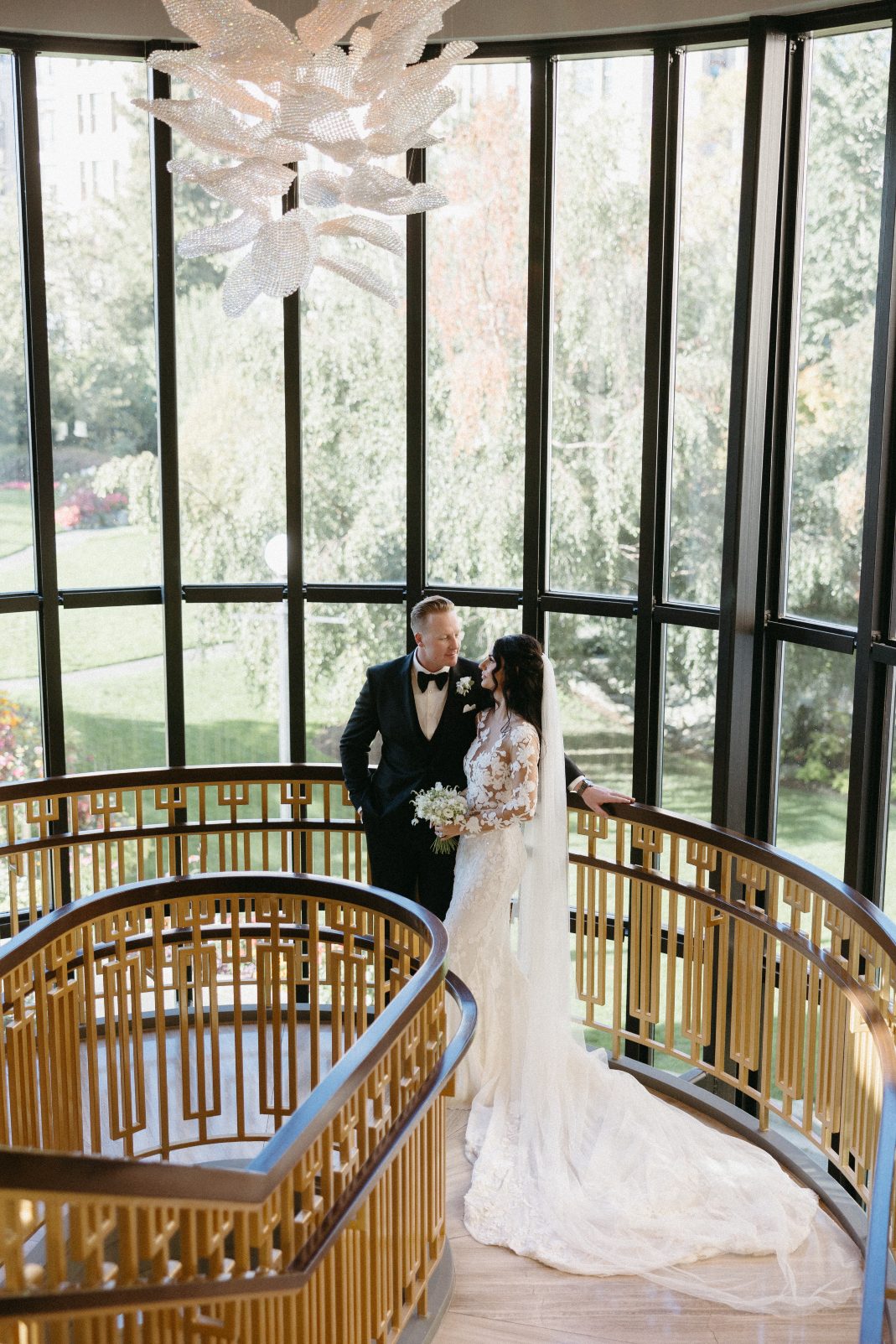 The beautiful couple gazing lovingly at each other on the landing of a cool curved staircase at the Fairmont Empress
