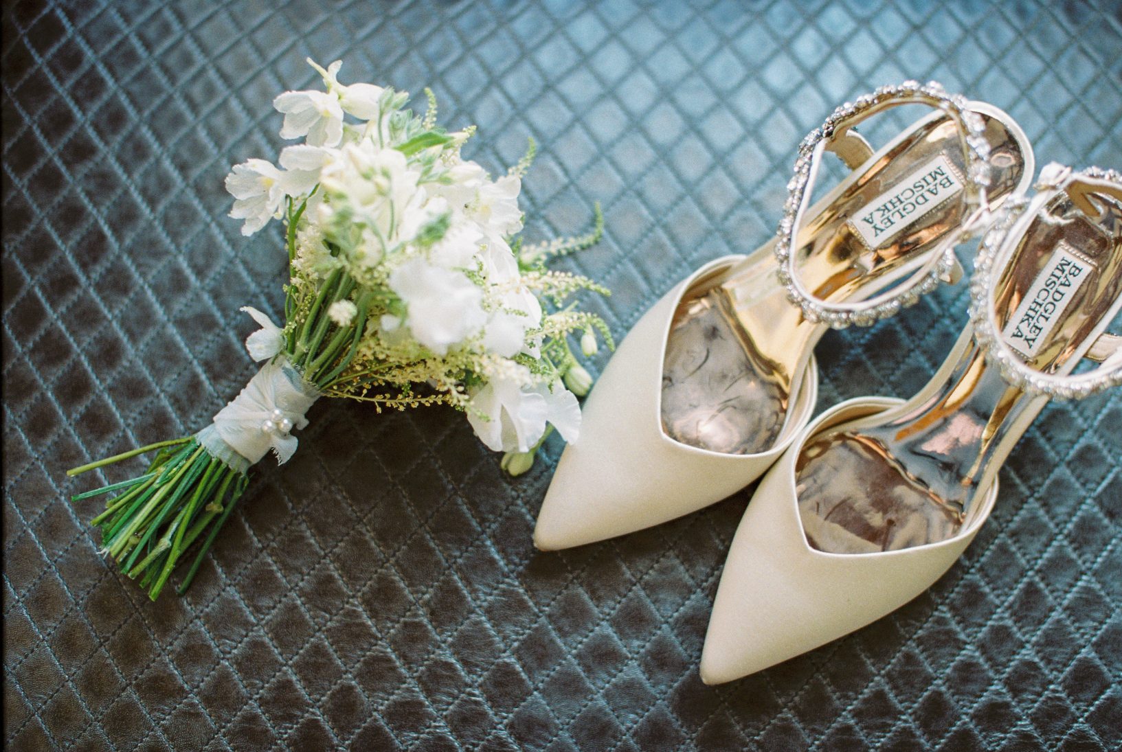 A detail shot of the bride's trendy white posy bouquet and her designer shoes