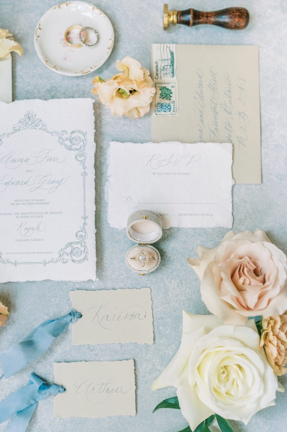 A flat lay shot of the stationary and ring accented by peach, blush and white flowers