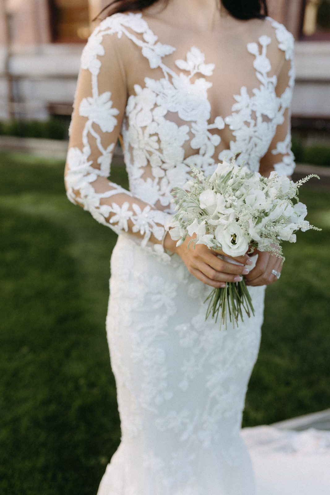 A close up of a beautiful Calyx bride's ornate gown, holding her delicate white posy bouquet