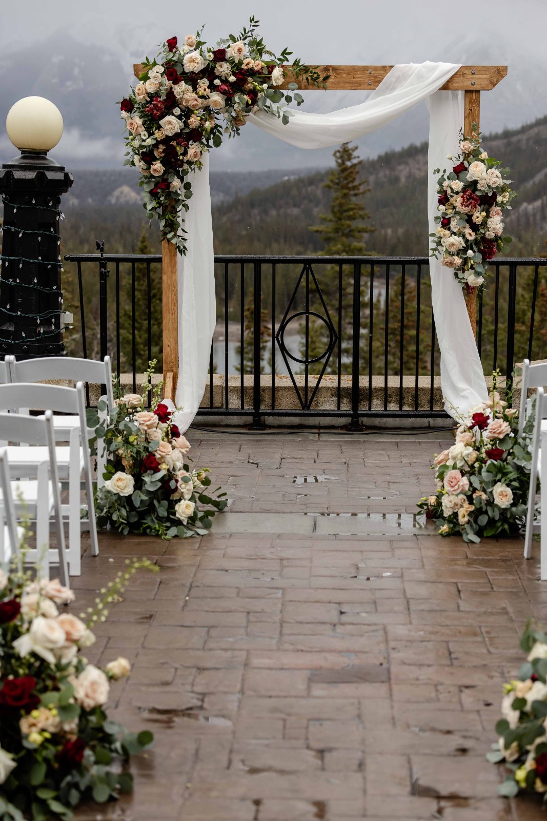 A shot of the ceremony set up with a beautiful asymmetrical archway and aisle arrangements with a mountain view in the background