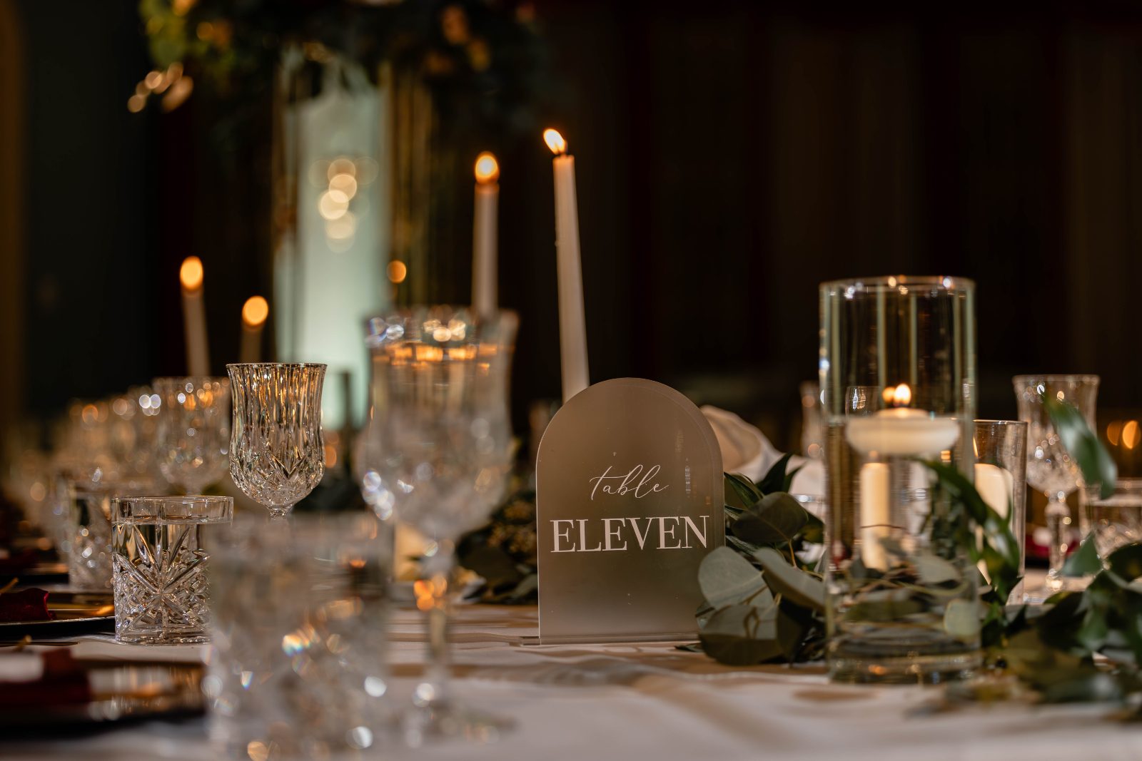 A lovely detail shot of the tables showing crystal glasses, candles and glass table numbers