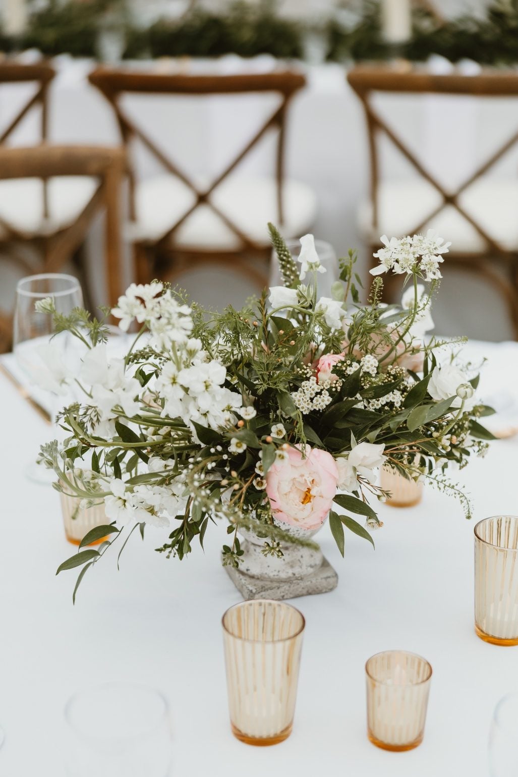 Compote Centrepiece A close up of one of the round table centrepieces featuring peonies, roses, stock, sweet peas, orlaya, lysmachia, spirea, and wax flower