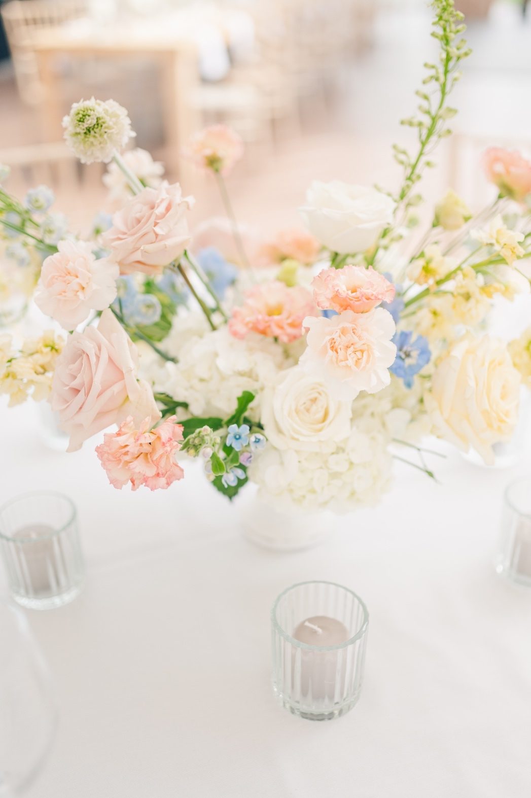 A shot of one of the pastel compote centrepieces featuring roses, stock, delphinium, lisianthus, carnations, scabiosa, hydrangea, roses and forget me nots.