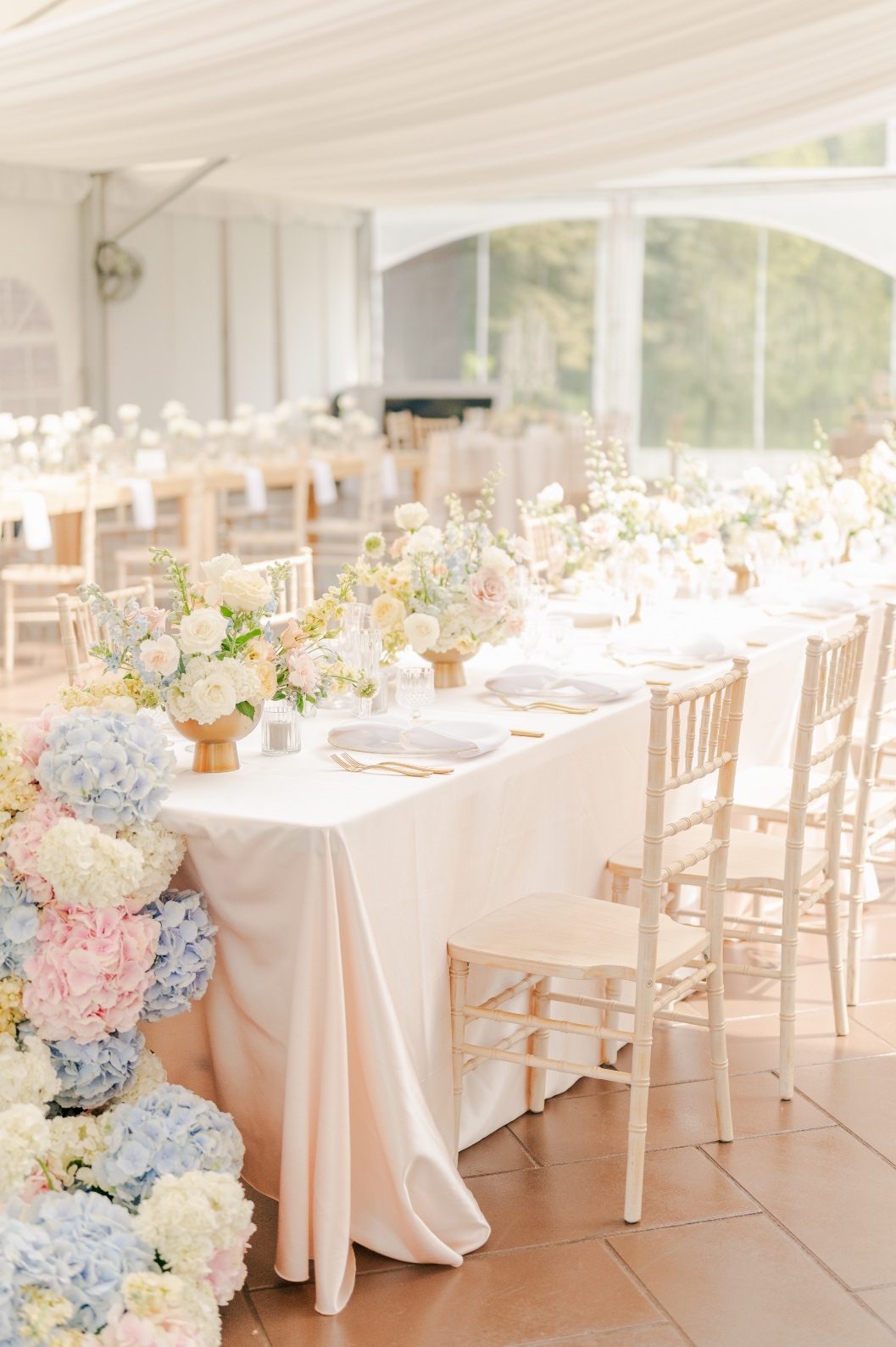 A long table set up with a row of beautiful, pastel compote centrepieces