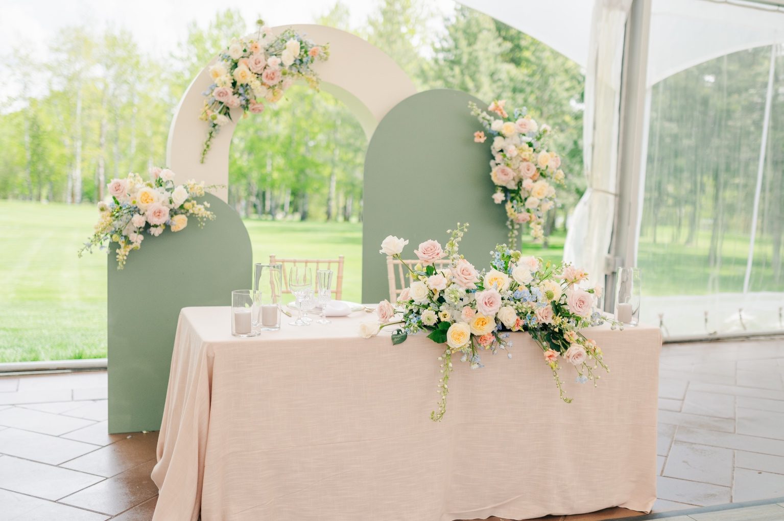 A view of the sweetheart table for a Bride + Groom, with a cool, modular backdrop adorned in pastel floral pieces.
