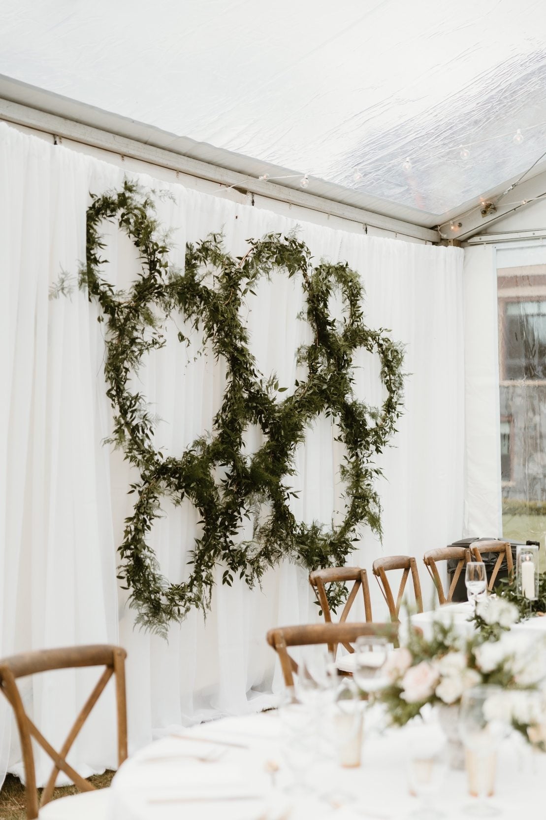 Hoop Wall Accent Gold hoops in various sizes are loosely covered in viney greenery and assembled together as a floral decor backdrop.