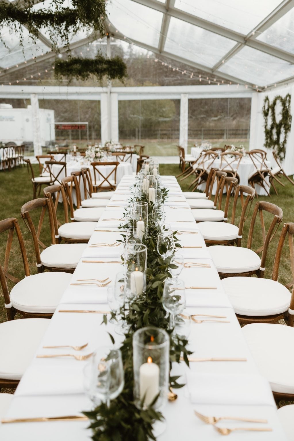Long Tables One of the long rectanular tables, displaying a fully garland down the center with ivory pillar candles in vases tucked in amongst the greens.