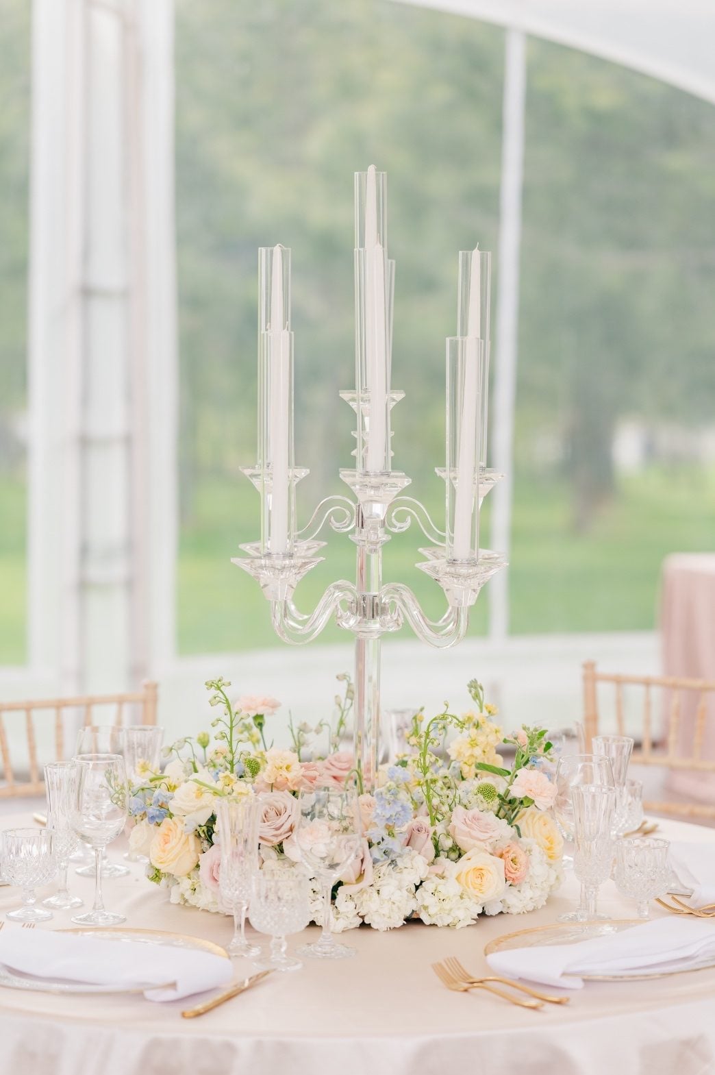 A large, full floral wreath as a centrepiece with a crystal candelabra with white tapers in the center.