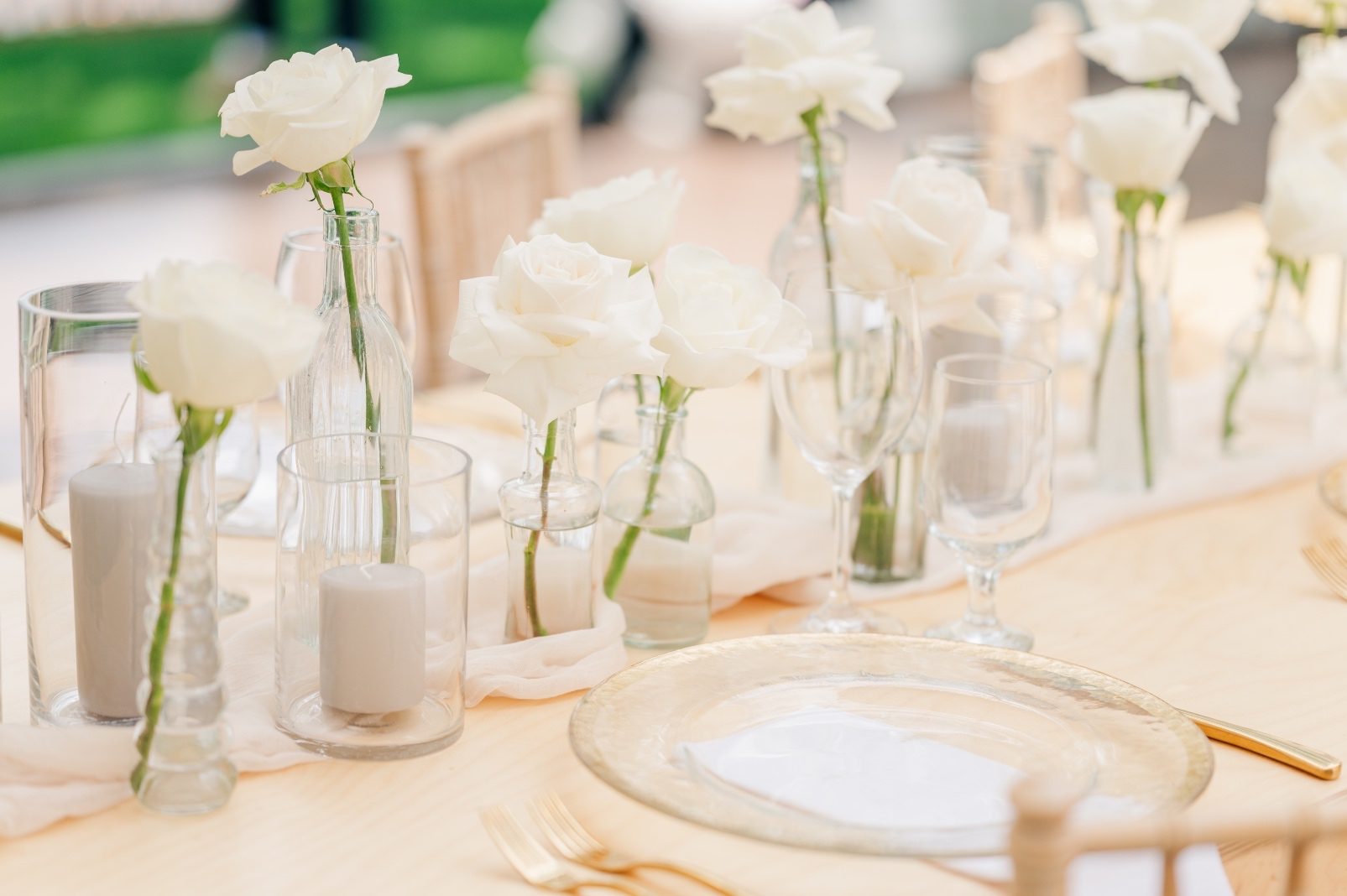 Assorted budvases running down the length of the table with taupe silk runner, and cylinder vases with candles.