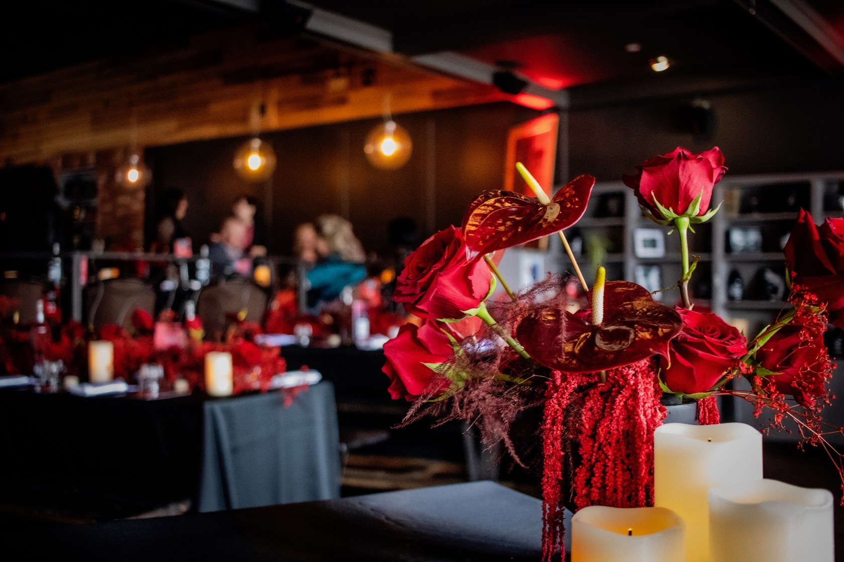 Table centrepieces at the Mustard Seed celebration. A modern, monochromatic red design of roses, anthurium, amaranthus, plumosa, and babies breath.