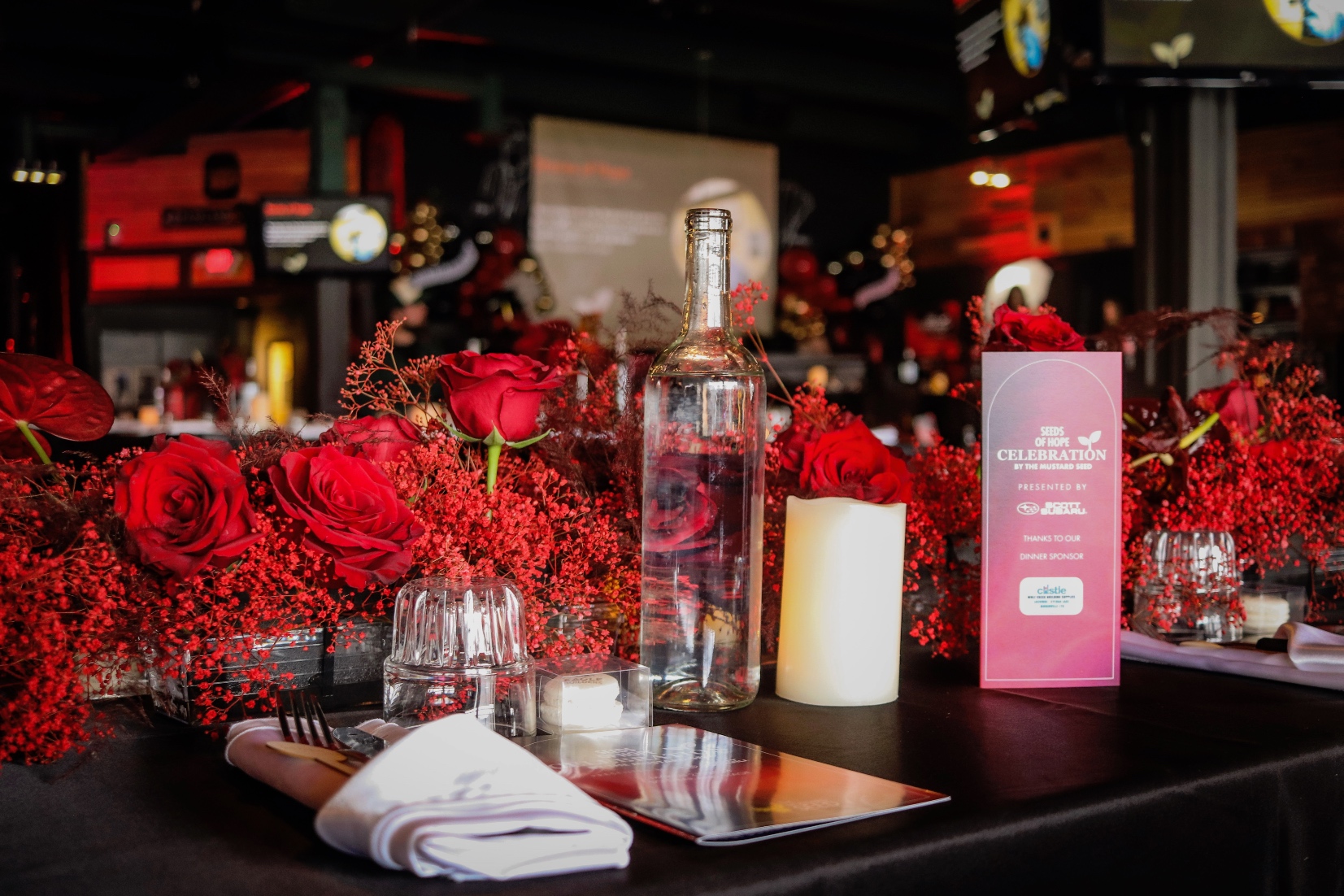 The long tables at the Mustard Seed event featured monochromatic red table garland of babies breath, plumosa and roses.