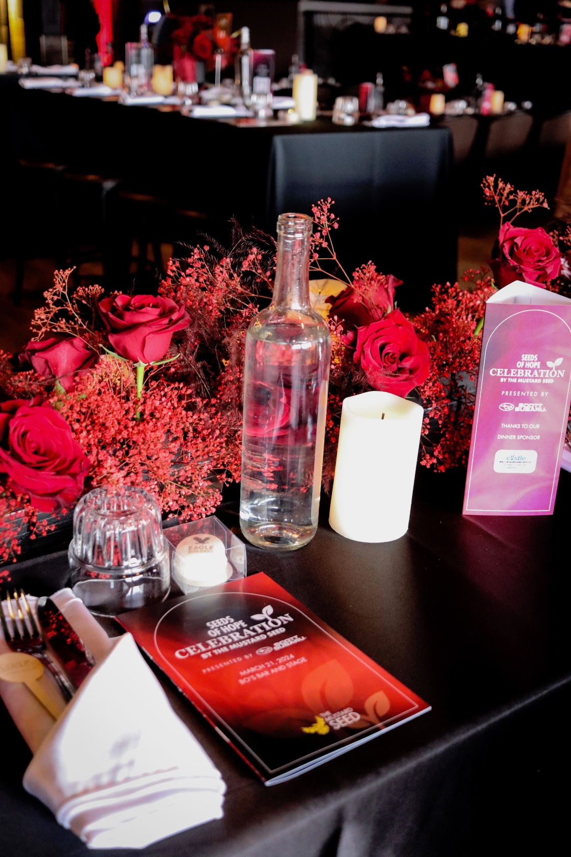 A floral garland down the long tables at the Mustard Seed celebration, made primarily of sprayed red babies breath, red plumosa accented with big beautiful red roses.