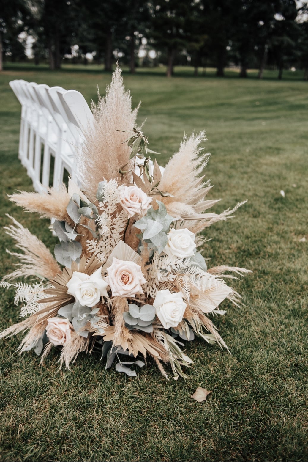 The gorgeous aisle arrangement with pampas grass, eucalyptus, roses, bleached greenery and olive branches.