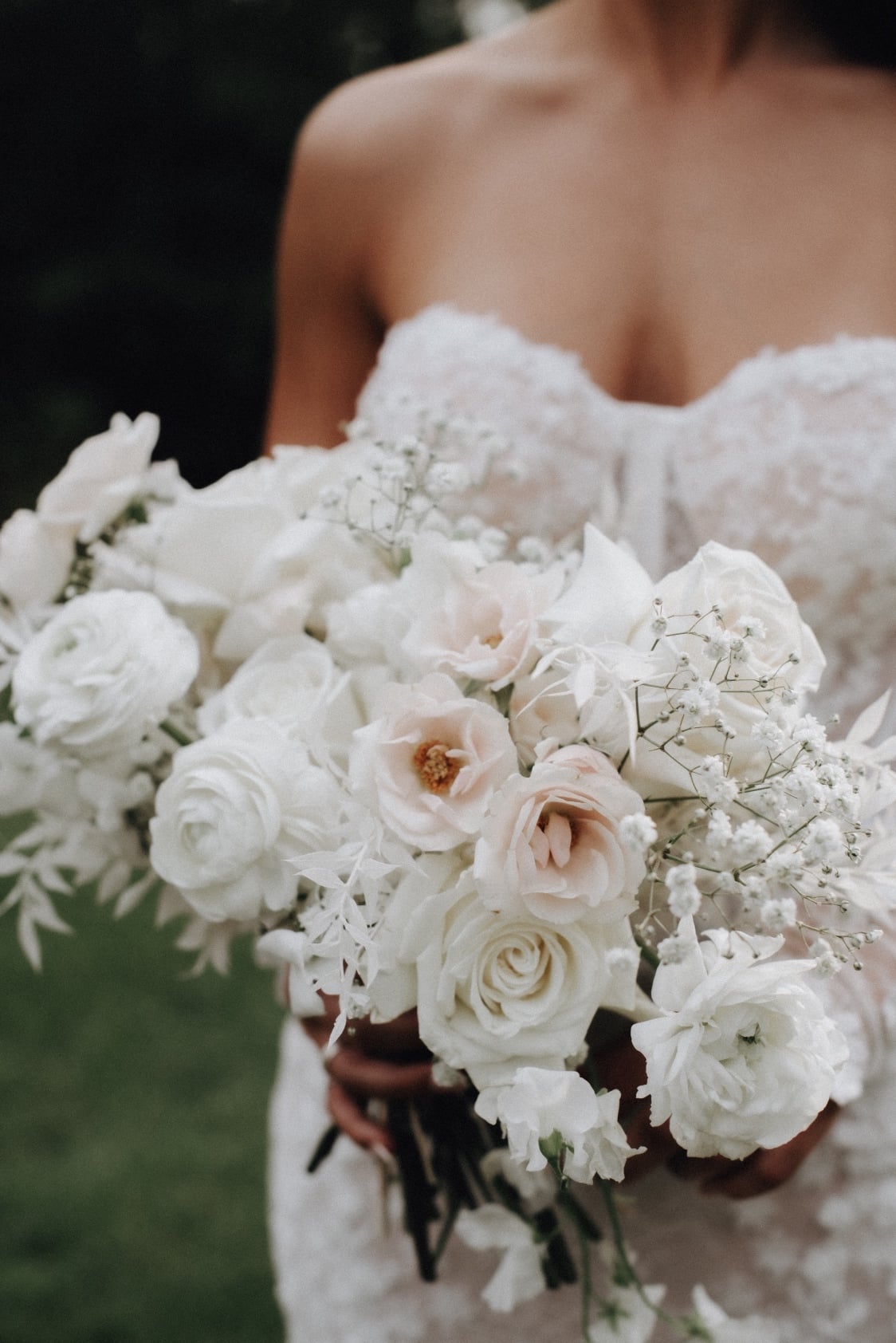 Bouquet Tianna holding her white and ivory bouquet of roses, lisianthus, ranunculus, sweet peas, baby's breath and bleached ruscus.