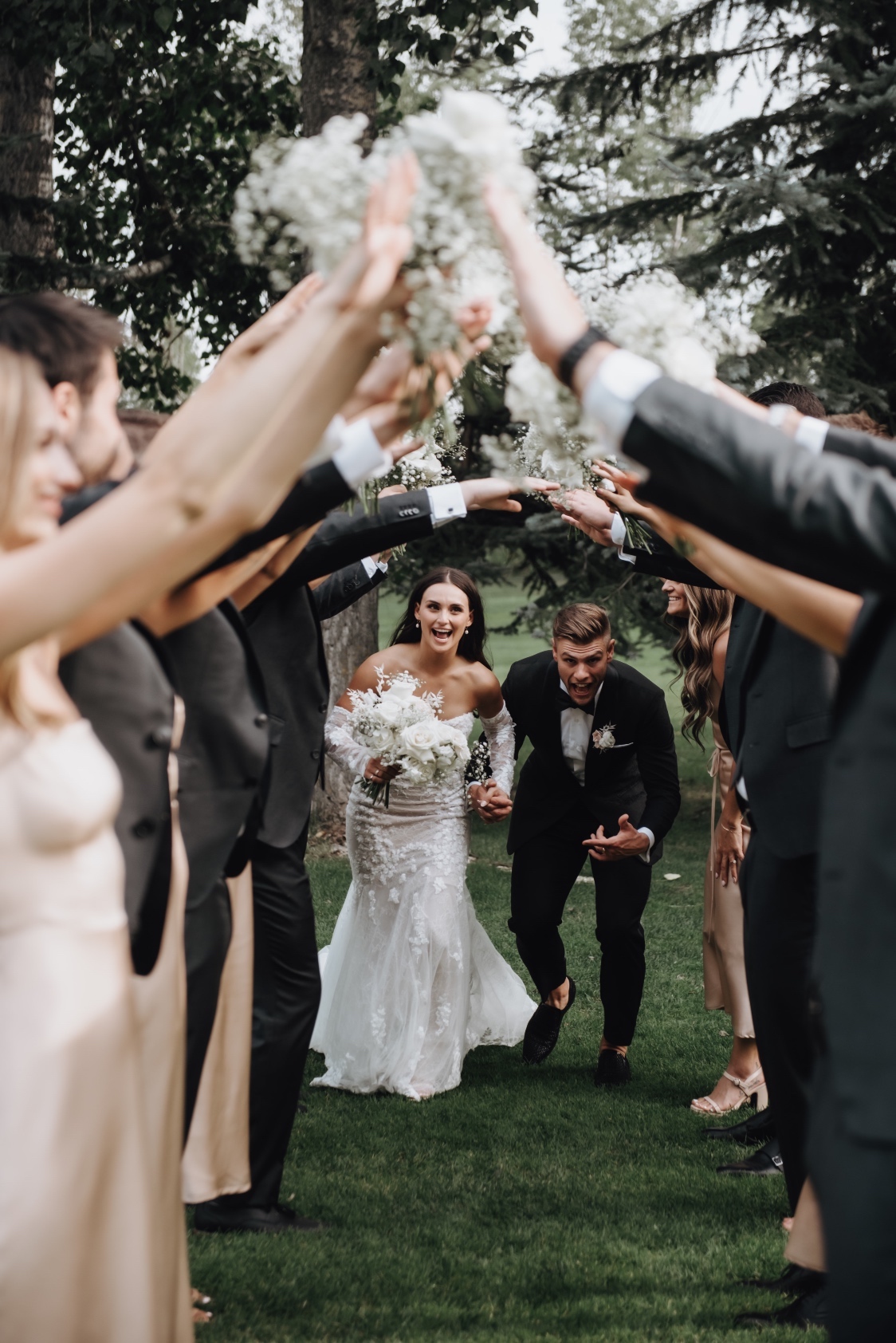 Bridal Party Fun The wedding party has created a "bridge" with their arms tented up as the bride and groom run through.
