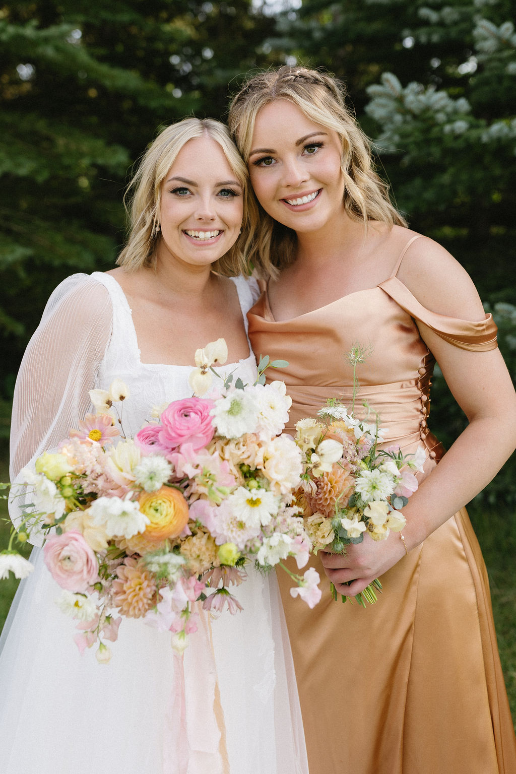 McKinley and one of her bridesmaids standing close together smiling and holding their bouquets.