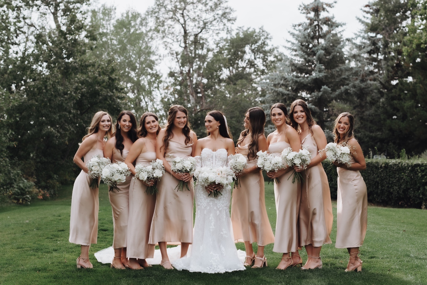 Bridesmaids Tianna and all eight of her bridesmaids standing together smiling and holding their bouquets.