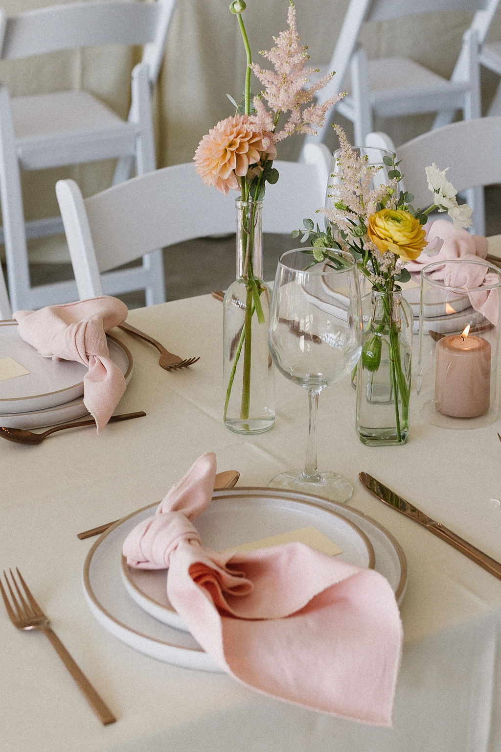 Cute gardeny bud vase centrepieces with beautiful peach and pink blooms with little tucks of greenery down the length of the tables.