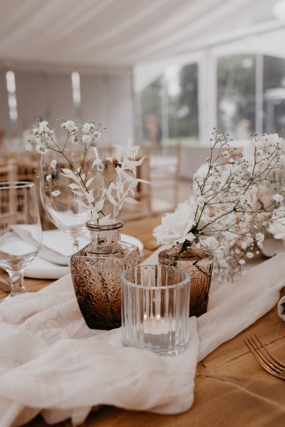 Budvase Another cluster of light brown bud vases with white blooms on the long tables.