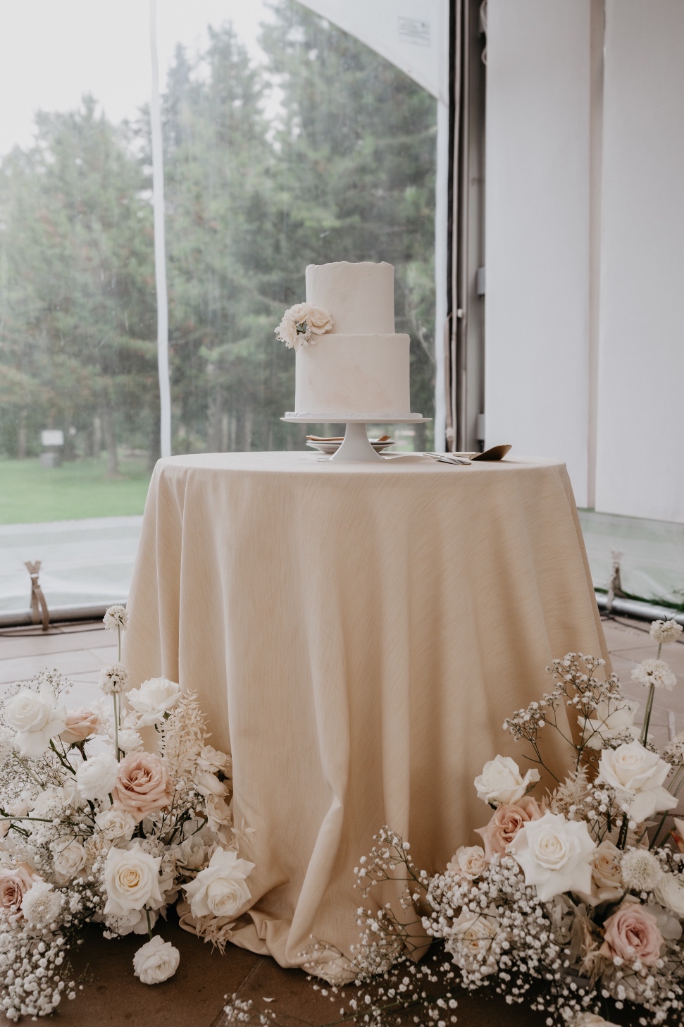 Cake Table The simple, two tiered cake on a small round table with two of the big arrangements from the ceremony displayed at the base.