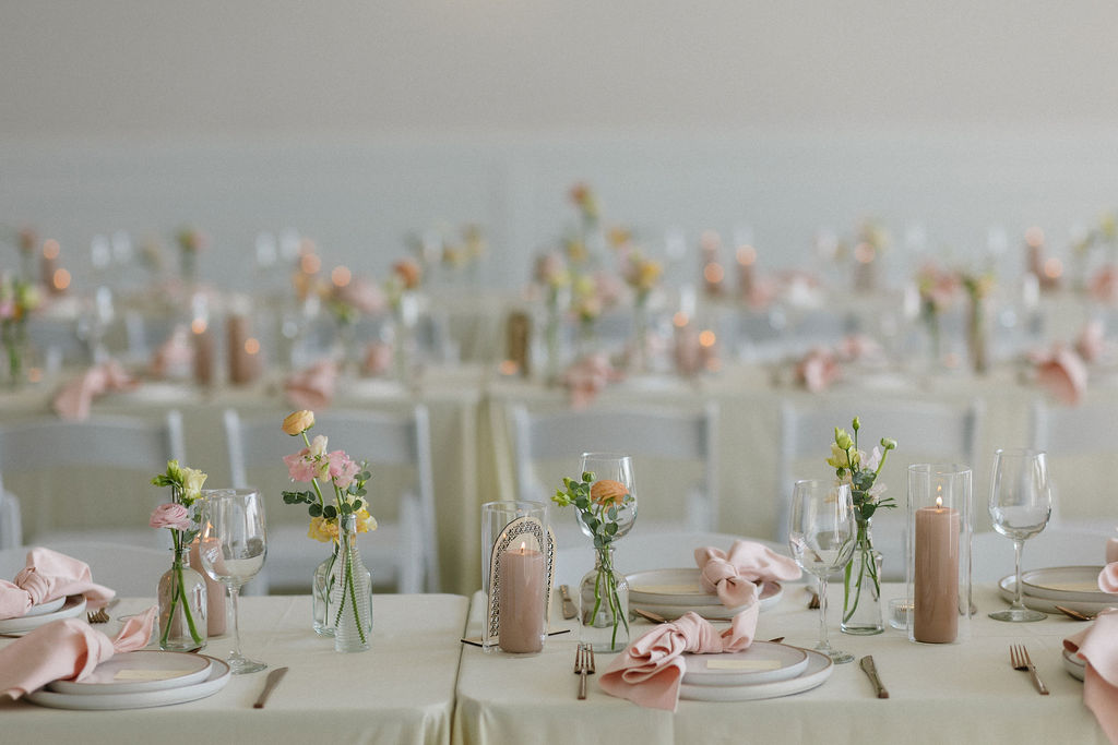 Crisp white tables and chairs accented with pinks, blush and peach with the napkins, bud vases and pillar candles.