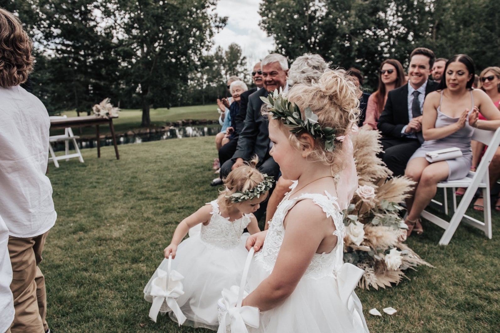 Adorable flower girls with flower crowns coming down the aisle and scattering petals