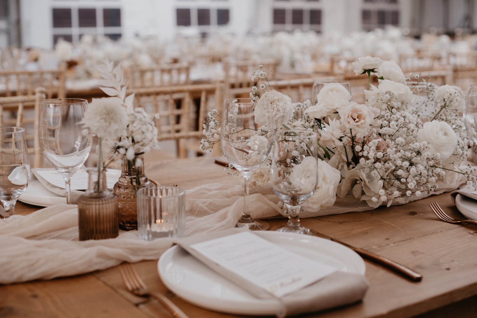 Long Tables The long wood tables with a mixture of low, elongated centrepieces alternated with clusters of assorted bud vase arrangements and votive candles.