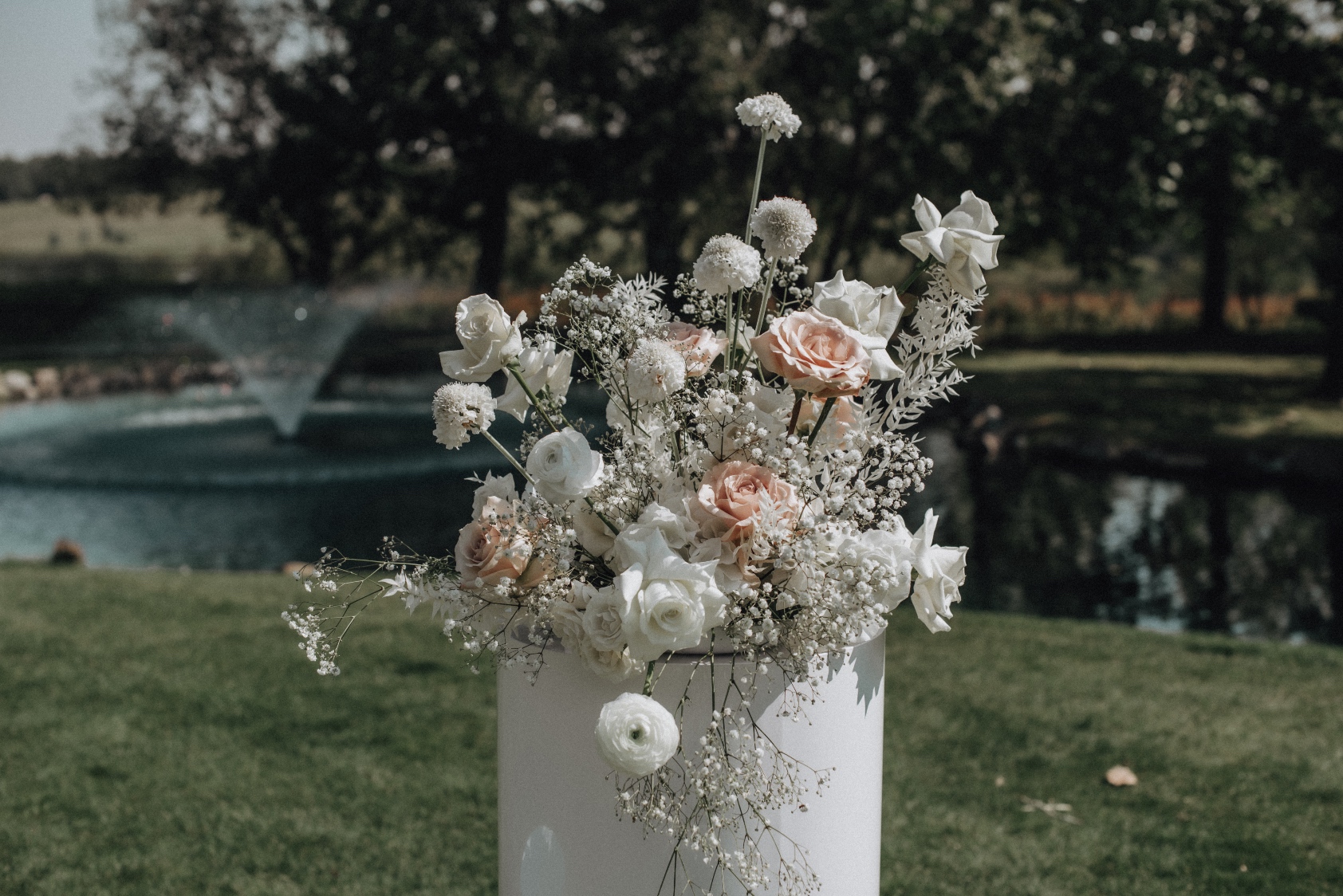 Pillar Arrangement Closer up shot of the arrangements on top of the pillars in a mixture of white, ivory and blush, full of tufts of baby's breath.