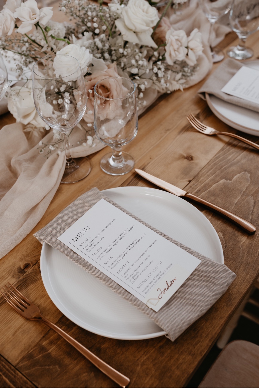 Table Setting A detail shot of the tablescap showing the beautiful wood tables, soft, gauzy table runner, low centrepieces and elegant place settings