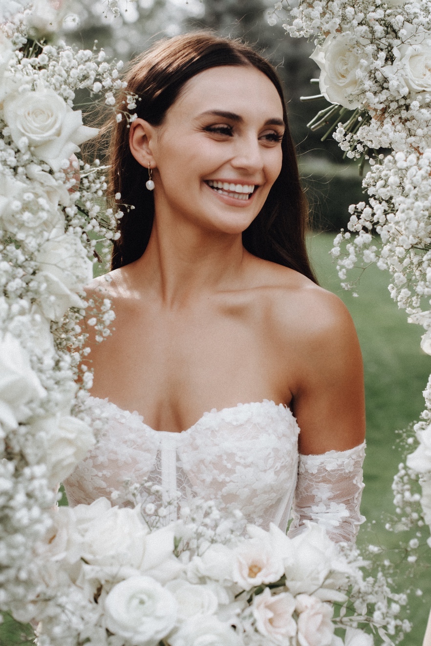 Tianna A close up of Tianna smiling, framed with baby's breath and roses, created by all the bridesmaids holding up their bouquets around her.