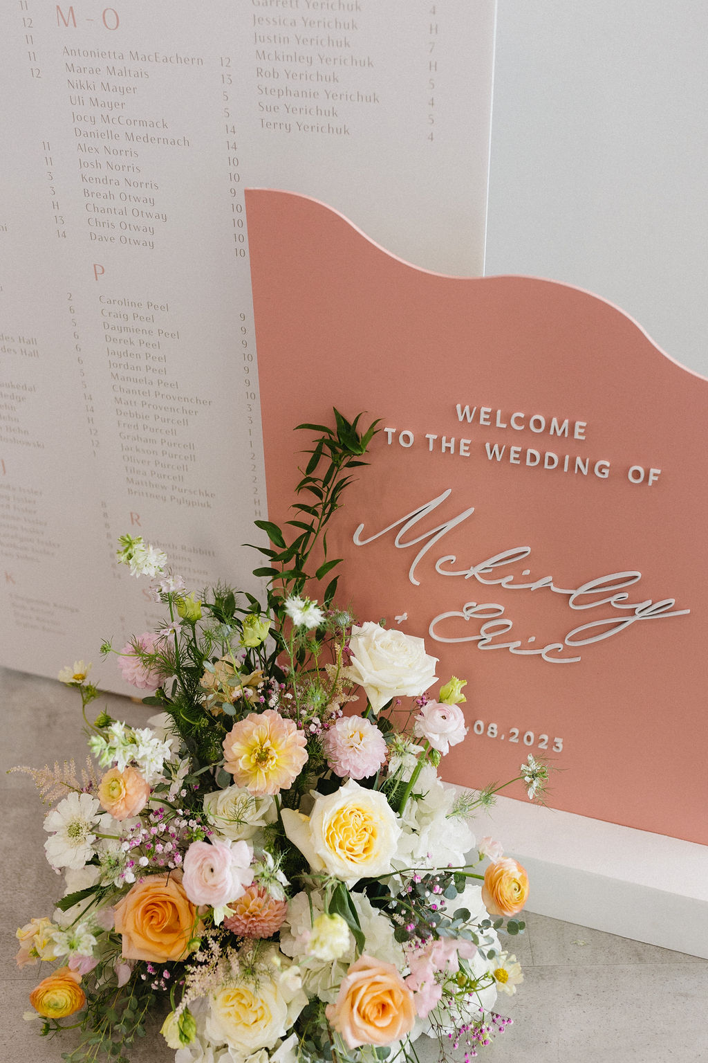 At the base of the welcome sign a gorgeous pastel floral arrangement full of roses, ranunculus, cosmos, sweet peas, italian ruscus, dahlias, lisianthus and astilbe.