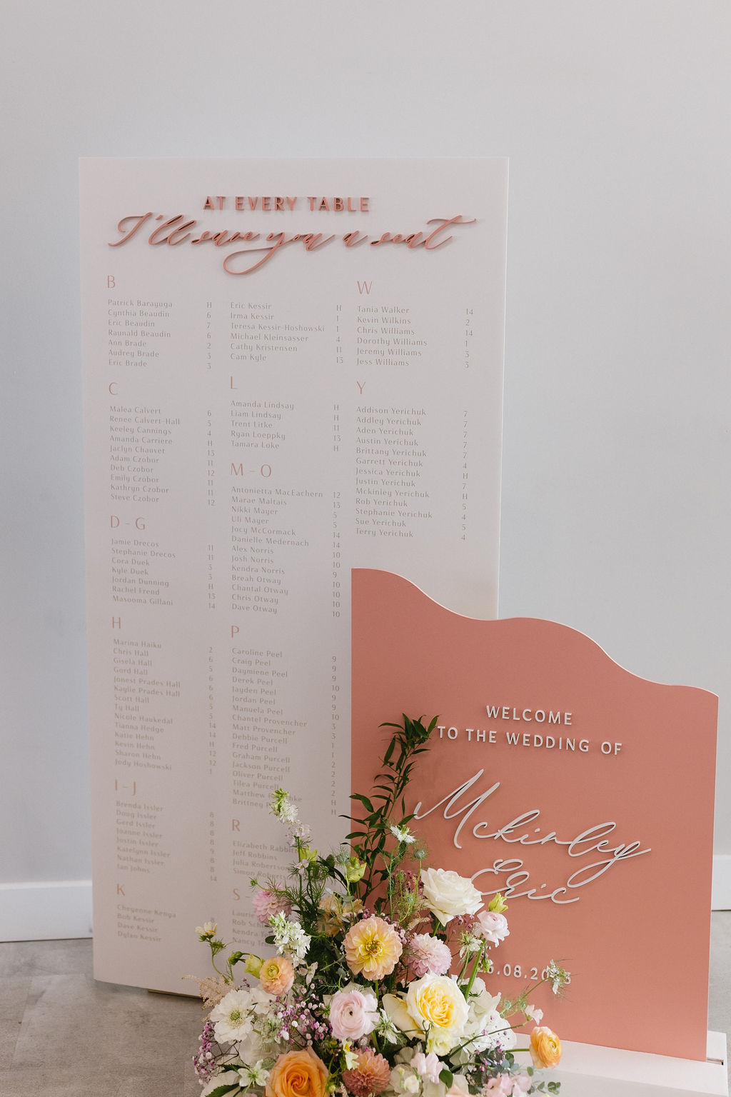A welcome sign and seating chart for guests as they arrive at the reception, adorned with a pastel floral arrangement.