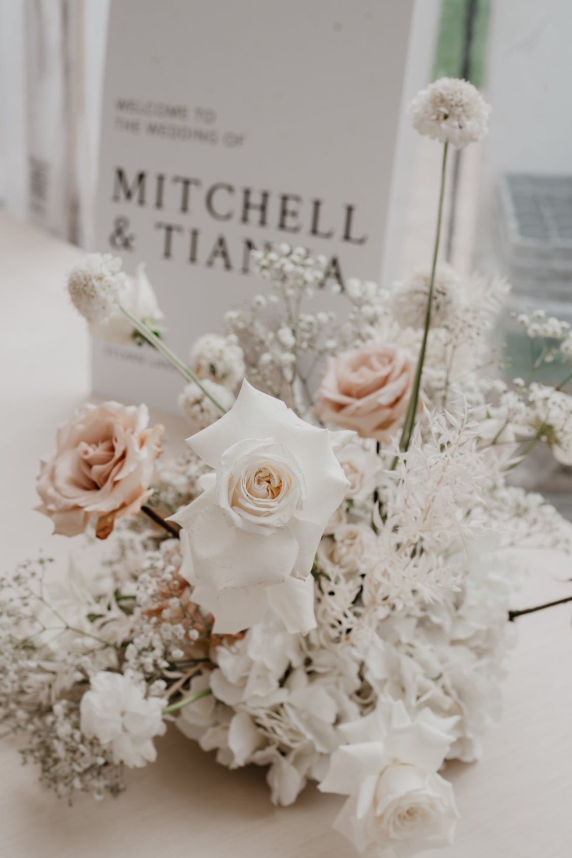 Welcome Sign A detail shot of the guest book table arrangement showing beautiful roses, baby's breath, scabiosa , and bleached ruscus.