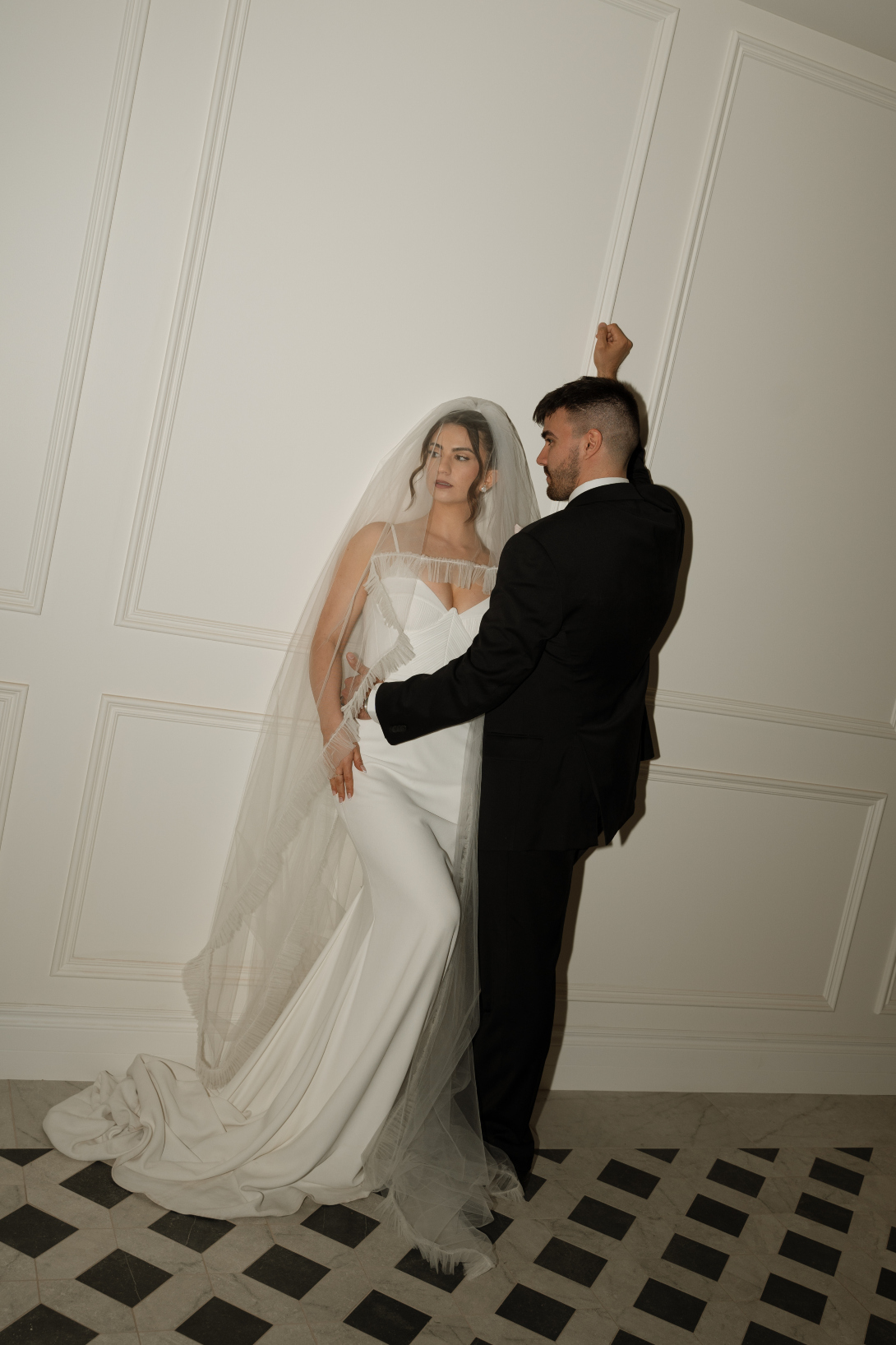 The couple embracing indoors for a photos, showing off the beautiful tile work and wainscoting details