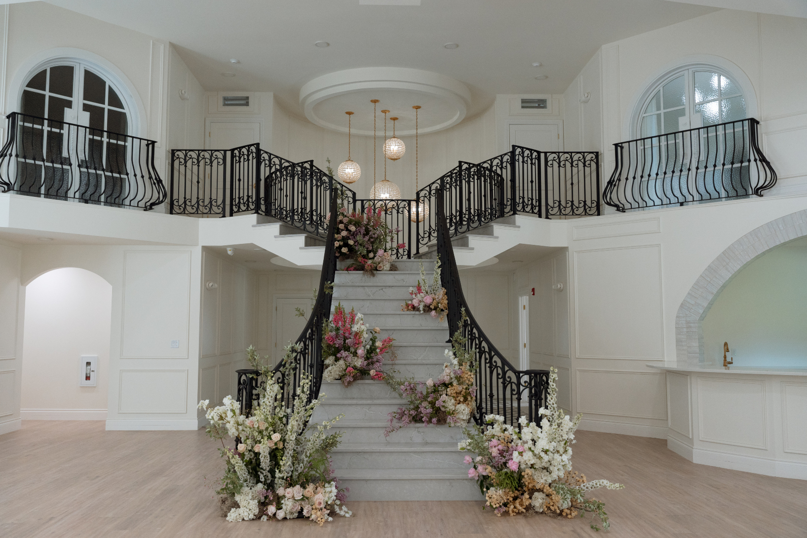 Gorgeous photo showcasing the dramatic grand staircase, with the wrought iron railings, juliette balconies and crystal chandelier.