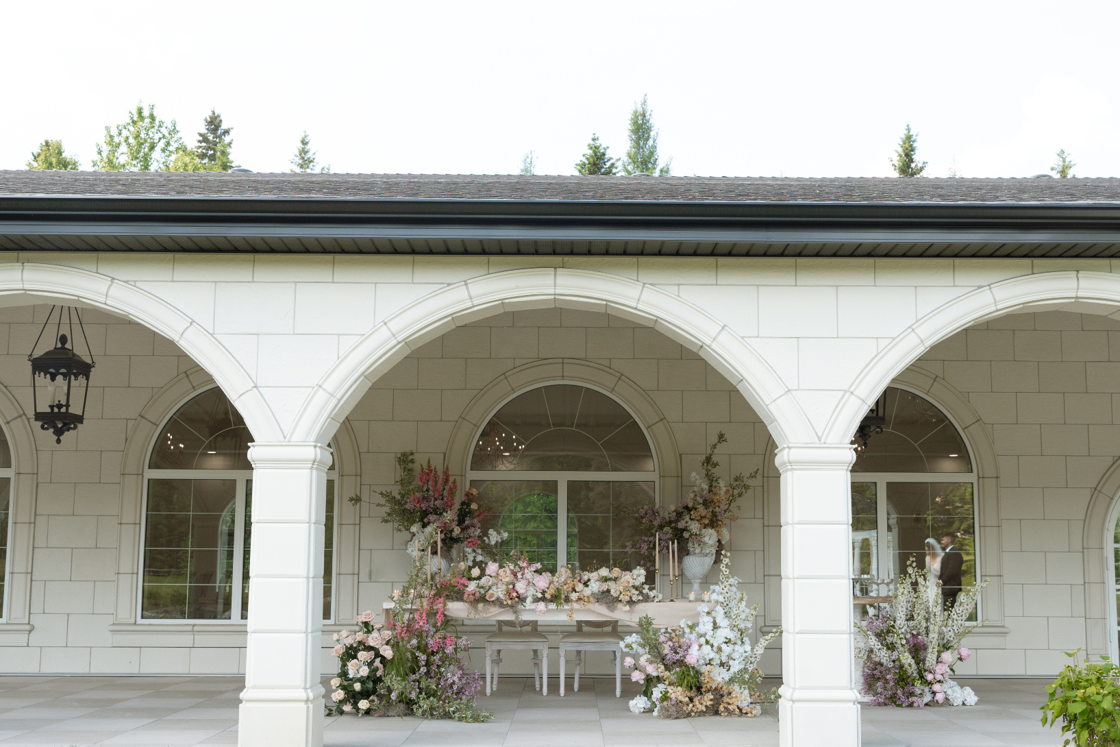 Outside the terrace, looking in through one of the arches, with a beautiful sweetheart table decked out in flowers.