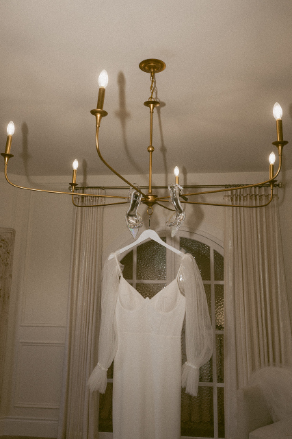 The brides stunning gown hanging from the unique light fixture in the bridal suite